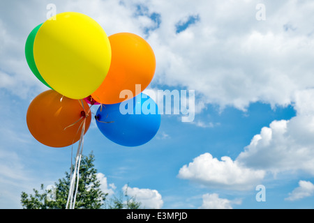 Bunte gefüllt Partei Heliumballons schwebend, angebunden vor einem sonnigen Sommer-Himmel Stockfoto