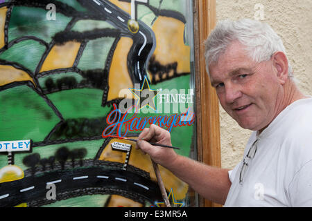 Skipton nach Harrogate, Yorkshire Dales National Park, Großbritannien. Eddie Ralph, lokale Künstler, seine Malerei Fenster Kunst als Yorkshire für Le Tour de France, der Zyklus artwork Route bereitet ist mit gelben Fahrräder und Banner als Unternehmen gestaltet sich für die weltweit größte Radrennen, die in der Grafschaft am 5. und 6. Juli 2014 beginnen wird, Millionen von Fans zu den Yorkshire am Straßenrand auf den Meistern der Sport zum Jubeln. Es ist das erste Mal, Le Tour im Norden von England besucht hat vorher nur Besuche an der Südküste und der Hauptstadt. Stockfoto