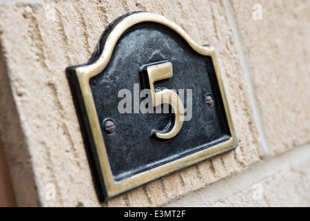 Eine Messingplakette Anzeige der Nummer 5 montiert an der Wand eines Hauses identifizieren die Häuser-Adresse Stockfoto