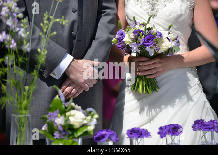 Eine Nahaufnahme von einer Braut mit Blumenstrauß & Bräutigam in traditioneller Kleidung während einer traditionellen Hochzeit Stockfoto