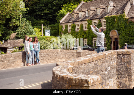 Touristen posiert auf der Brücke über den Fluss Coln & das Swan Hotel in der hübschen Cotswold Dorf Bibury, Gloucestershire, UK Stockfoto