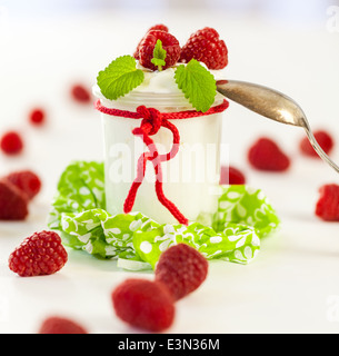 Frische reife Himbeeren serviert mit einem Glas des gesunden Joghurt oder Clotted Cream für ein leckeres Dessert oder Frühstück mit copysp Stockfoto