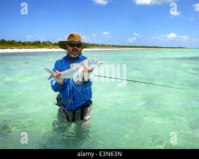 Fliegenfischer mit Bonefish erwischt beim Salzwasser Fliegenfischen im Urlaub auf Mayaguana Island auf den Bahamas Stockfoto