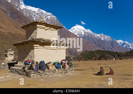 Porter lädt auf eine STUPA in einem hoch gelegenen Tal in der Nähe von SAMAGAUN auf der ganzen MANASLU Trekking - NUPRI REGION NEPALS Stockfoto