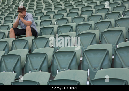 Trauriger Mann sitzt allein im leeren Stadion Stockfoto