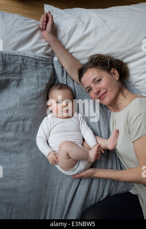 Hohen Winkel Porträt von Mutter und Baby Mädchen auf der Matratze liegend Stockfoto