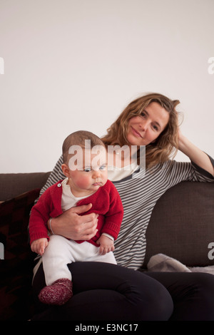 Porträt der Frau sitzt mit Babymädchen zu Hause auf sofa Stockfoto