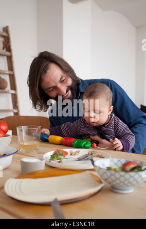 Glücklicher Vater mit Babymädchen spielen am Tisch Stockfoto