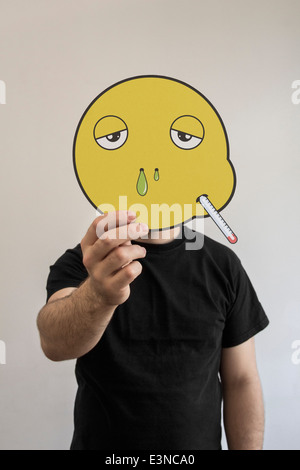 Mann, der ein kranker Smiley Gesicht vor sein Gesicht hält Stockfoto