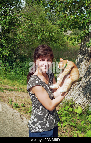 Lebensstil der ländlichen Sommer 2013. Die Bewohner des Dorfes - das Mädchen und der rot-Orange Katze auf der Dorfstraße. Stockfoto