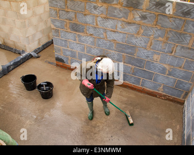 Selbstbau-Haus, Frau fegt nassen Boden sauber zu halten den Bau Website ordentlich Stockfoto
