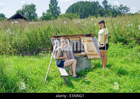 Lebensstil der ländlichen Sommer 2013. Bewohner des Dorfes - Mädchen und rot-Orange Katze in der Nähe eines Brunnens. Stockfoto