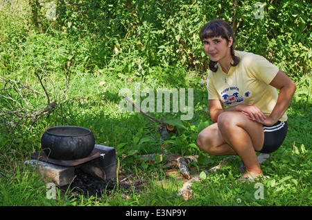 Lebensstil der ländlichen Sommer 2013. Bewohner des Dorfes - das Mädchen in der Nähe von einem gusseisernen Kessel in einem Garten. Stockfoto