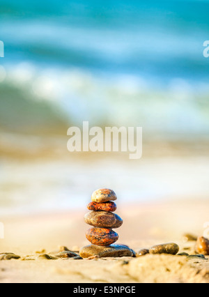 Steinen Pyramide auf Sand als Symbol für Frieden und Harmonie, blauen Ozean im Hintergrund. Stockfoto