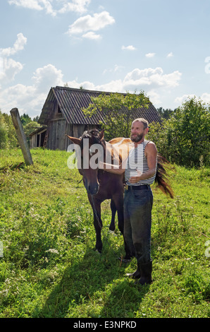 Klassische Heuernte in Belarus-Dorf. Pferd für den Transport von Heu auf den Wagen. Stockfoto