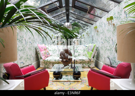 Zimmer "Garden" mit passendem Sofa Stoff und Tapete bestehend aus Papageien und Bambus. paar rosa 50er Jahre Sessel sitzen gegenüber Stockfoto