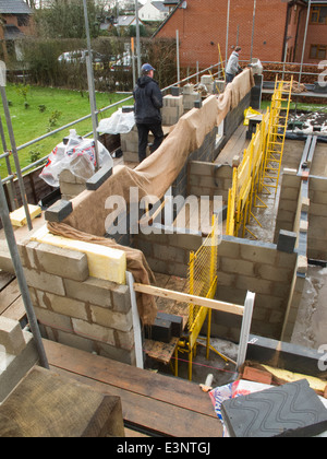 selbst Hausbau, Betonblöcke Maurer auf einem Gerüst Verlegung Obergeschoss außen Stockfoto