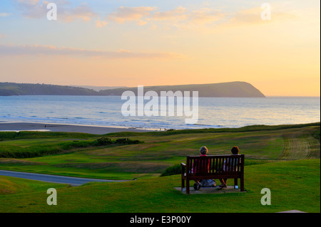 Newport Links Golf Club Sonnenuntergang, Frau auf der Bank mit Blick auf Dinas Kopf Halbinsel, Newport, Pembrokeshire, Wales, UK Stockfoto