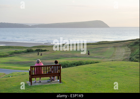 Newport Links Golf Club, Frau auf der Bank mit Blick auf Strand von Newport, Pembrokeshire, Wales, UK Stockfoto