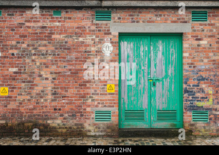Vorhängeschloss grüne Tür in einem alten Backsteingebäude Stockfoto