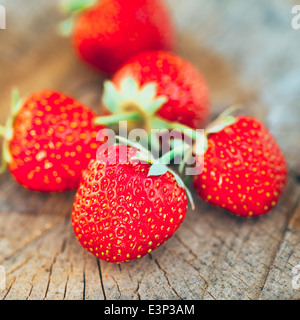 Erdbeeren. Bio-Beeren Nahaufnahme. Saftig frische reife rote Erdbeeren auf einer alten Birke stumpf. Getönten Bild Stockfoto