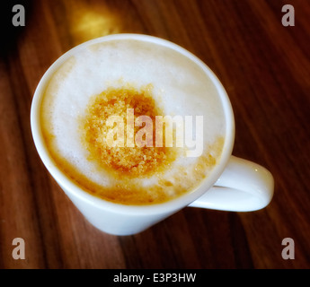 Eine Tasse Cappuccino mit braunem Zucker obenauf schwimmende Stockfoto