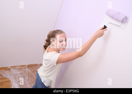 Mädchen-Farben Wand in lila Farbe mit Walze, horizontale Stockfoto