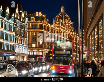 Das Kaufhaus Harrods in der Abenddämmerung mit beleuchteten "Sale" Schild Shopper rot Bus und verkehrsreichen Knightsbridge London SW1 Stockfoto