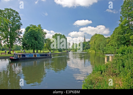 Eine blaue schmale Boot am Fluss Avon in Stratford-upon-Avon, mit dem Turm der Kirche der Heiligen Dreifaltigkeit über den Bäumen. Stockfoto