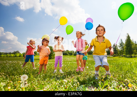 Kinder mit bunten Luftballons in Feld Stockfoto