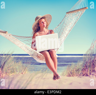 Schöne Frau sitzt auf einer Hängematte am Strand Stockfoto