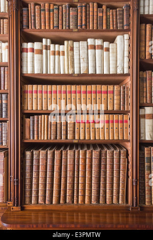 Antiquarische Bücher aufgereiht und fein säuberlich auf Bücherregale in Bibliothek an Tatton Park, Cheshire, UK Stockfoto