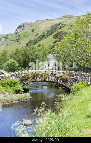 Traditionellen Trockenmauern Lastesel Brücke bei Watendlath, Borrowdale, Lake District mit ziemlich weiß getünchten Landhaus aus Stein gebaut Stockfoto