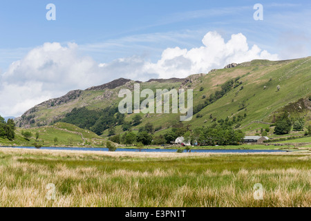 Watendlath Tarn, Borrowdale, Lake District, Großbritannien im Sommer mit Blick auf Bauernhof, Berge und blauer Himmel mit weißen flauschigen Wolken Stockfoto