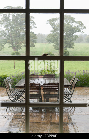 Verglaste Fenster, Blick zum Garten-Terrasse mit Gartenmöbel nass Stockfoto