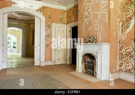 Alte Kamin im leeren Raum mit abblätternde Tapete und unsanded Etagen zugemauert Stockfoto