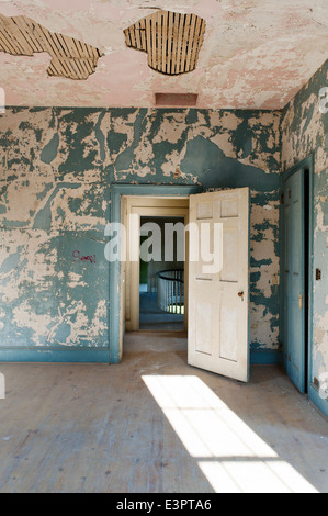 Offene Tür im Raum mit gerissenen und abblätternde Wandfarbe und fehlende Decke Putz Stockfoto