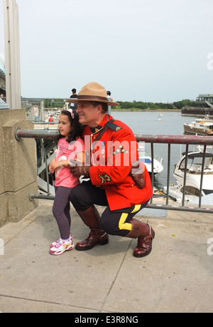 Ein junges Kind hat ihr Foto mit einem RCMP Offizier in Uniform während der Canada Day Feierlichkeiten in den alten Hafen von Montreal, Qu Stockfoto