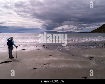 Einsamer Wanderer auf Camasunary Strand auf der Insel Skye, mit Blick über den Loch Scavaig auf die Insel Rum & Cloud Plume, Schottland, Großbritannien. Stockfoto