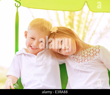 Glückliches kleines Kind spielen im Freien an sonnigen Tagen, Bruder mit Schwester Reiten auf Schaukel, aktive Sommerferien, Glück-Konzept Stockfoto