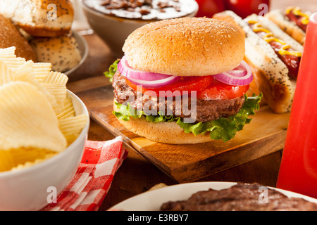 Herzhaftes vom Grill Hamburger mit Salat und Tomaten auf einem Brötchen Stockfoto