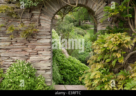 Peeping durch steinernen Torbogen zum Rasen Garten hinaus. Stockfoto