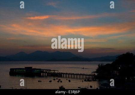 Sonnenauf- und Sonnenuntergang über der Lamma Island Ferry Pier, Yung Shue Wan, Lamma Island, Hong Kong, China. Kredit; Kraig LIeb Stockfoto