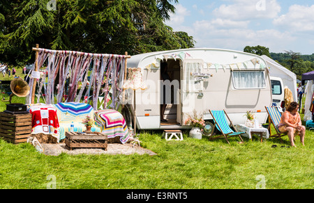 East Devon, England. Eine Frau sitzt auf einem Liegestuhl außerhalb ihrer alten Vintage Wohnwagen auf einer Fete in ein Landhaus. Stockfoto