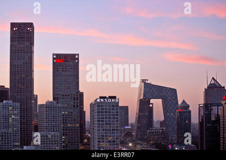 Schöner Blick auf die Skyline von Jianwai Soho und das berühmte Wahrzeichen des CCTV-Hauptquartiers, mit den Lichtern des Verkehrs auf der dritten Ringstraße und Büros und Gebäuden, die die Szene am frühen Abend erhellen. Seltene Panorama-Szene während der blauen Stunde kurz nach Sonnenuntergang mit klarem Himmel in Guomao, dem zentralen Geschäftsviertel der chinesischen Hauptstadt Peking, befindet sich im Chaoyang Bezirk, China, PRC. © Olli Geibel Stockfoto