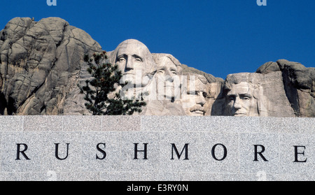 Die Gesichter der vier US-Präsidenten geschnitzt auf einen Berg Blick über ein Zeichen von Mount Rushmore National Memorial in den Black Hills von South Dakota, USA. Stockfoto