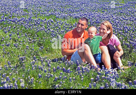 Ein junges Paar und ihre spielerische Sohn entspannen Sie an einem sonnigen Tag in einem Feld von Kornblumen, die amtliche Zustandblume von Texas, USA. -Modell veröffentlicht. Stockfoto