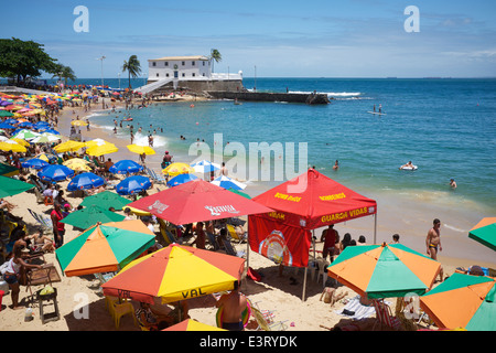 SALVADOR, Brasilien - 13. Oktober 2013: Beachgoers versammeln sich unter bunten Sonnenschirmen am hellen Nachmittag am Porto da Barra. Stockfoto