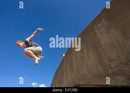 Teenboy springen Saltos Sequenz gegen blauen Himmel im Naturpark our Turnerin Aktivitäten im Freien am Strand Stockfoto