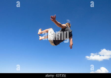 Teenboy springen Saltos Sequenz gegen blauen Himmel im Naturpark our Turnerin Aktivitäten im Freien am Strand Stockfoto